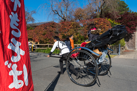 KYOTO,JAPAN-NOV26:Unidentified tourists on rickshaw enjoy autumn colors along Hozu gawa river at Arashiyama in Kyoto on November 26,2106.Arashiyama is a one of attraction landmark for tourists.のeditorial素材