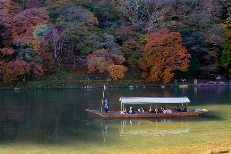 KYOTO,JAPAN-NOV26:Unidentified tourists on wooden boat enjoy autumn colors along Hozu gawa river at Arashiyama in Kyoto on November 26,2106.Arashiyama is a one of attraction landmark for tourists.のeditorial素材