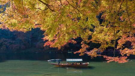KYOTO, JAPAN - NOV 26 : Unidentified tourists on wooden boat enjoy autumn colors along Hozugawa river at Arashiyama in Kyoto on November 26, 2106. Arashiyama is a one of attraction landmark for tourists.のeditorial素材
