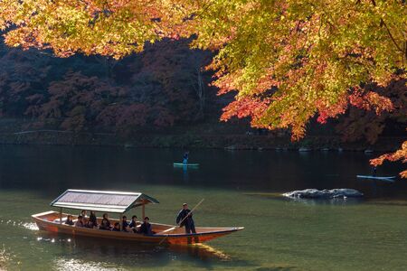 KYOTO,JAPAN-NOV26:Unidentified tourists on wooden boat enjoy autumn colors along Hozu gawa river at Arashiyama in Kyoto on November 26,2106.Arashiyama is a one of attraction landmark for tourists.のeditorial素材