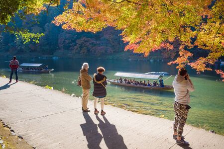 KYOTO,JAPAN-NOV26:Unidentified tourists watching autumn colors along Hozu-gawa river at Arashiyama in Kyoto on November 26,2106.Arashiyama is a one of attraction landmark for tourists.のeditorial素材