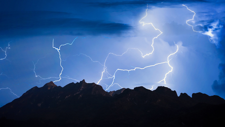 Panorama view of thunder storm lightning strike over mountain with dark cloudy sky background at night.の写真素材