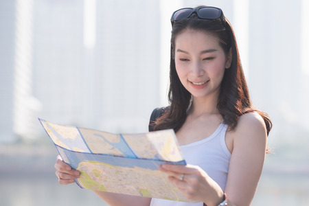Beautiful asian solo tourist woman  looking at the map searching for tourists sightseeing spot....