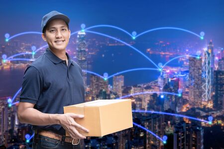 Asian delivery man holding a cardboard box with networking of internet of things in smart city for...