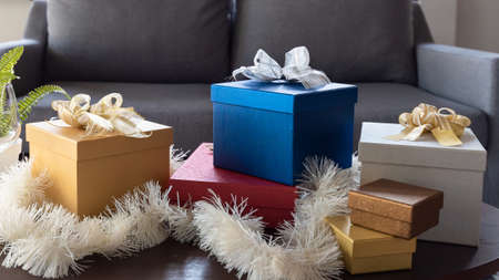 Beautiful Christmas gift boxes wrapped in colourful paper with ribbon bow on table in living room at homeの写真素材