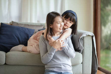 Asian mother make love with warm hug her cute daughter at homeの写真素材