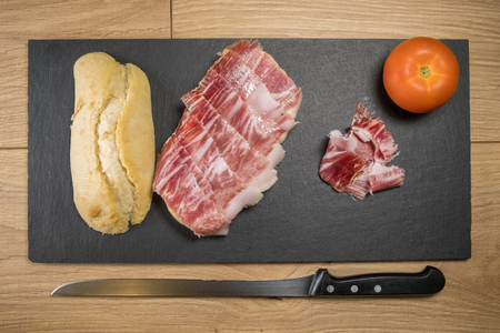 Iberian ham sandwich © rico de bellota with carving knife and tomatoの写真素材