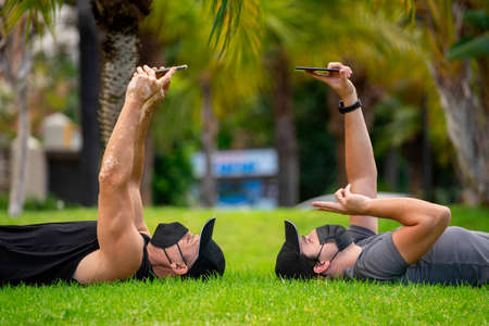 Men in masks in the park doing sport and taking a selfie with a smartphoneの写真素材