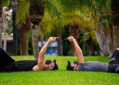 Men in masks in the park doing sport and taking a selfie with a smartphoneの写真素材