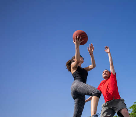 Friends, boy and girl having fun laughing and playing basketballの写真素材