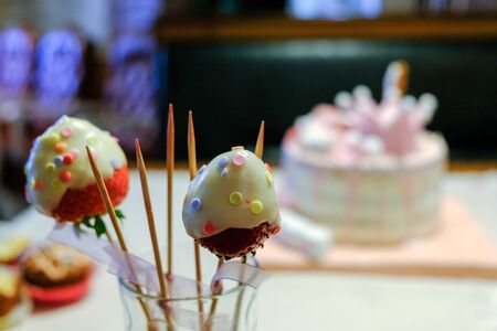 Tasty birthday party bites - fresh strawberries on wooden skewers covered with white chocolate and colorful sprinklesの写真素材