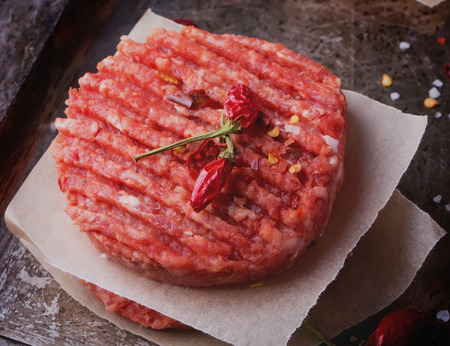 Raw Ground beef meat Burger steak cutlets with seasoning on vintage metal tray, black backgroundの写真素材