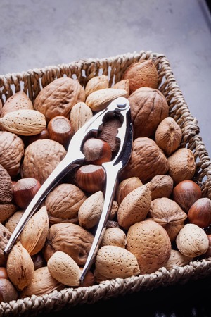 Selection of various nuts: almonds, Brazilian, walnuts on a vintage square basket with a nut cracker