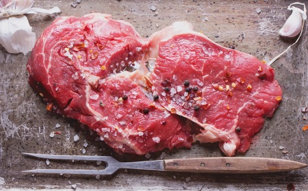 Raw fresh meat Ribeye Steak, with seasoning and meat fork on vintage metal trayの写真素材