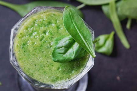 Glass of refreshing green smothie served with green apple, baby spinach leaves, soya sprouts and an egg yolkの写真素材