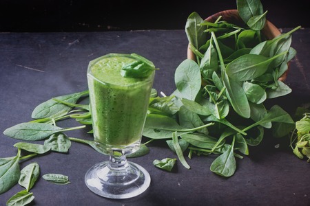 Glass of refreshing green smothie served with green apple, baby spinach leaves, soya sprouts and an egg yolkの写真素材