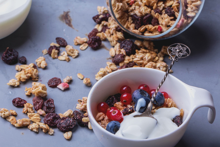 Home Made Granola breakfast with white plain yogurt, blueberries, redcurrant and dry cherries on metal backgroundの写真素材