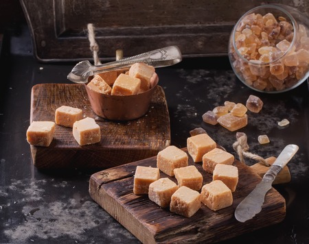 Rustic wooden boards with fudge candy glass sugar bowl, served with sugar cubes over dark backgroundの写真素材