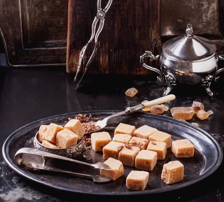 Vintage metal tray with fudge and truffle candies  glass sugar bowl, served with chocolate chips over dark backgroundの写真素材