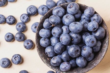 Blueberries in black metal bowls on rustic creamy wooden board