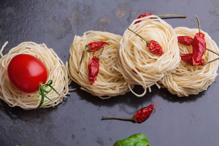 Home-made italian pasta nests with cherry tomatoes, pepperoni and basil leaves ready to cookの写真素材