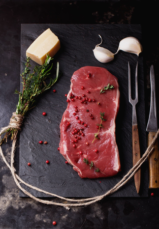 Raw fresh meat Striploin steak and seasoning on blackslate board over dark metal background, top viewの写真素材