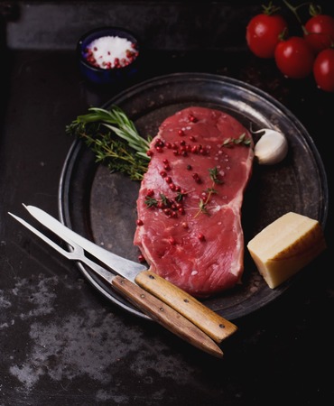 Raw fresh meat Striploin steak and seasoning on a rustic metal tray over dark metal background, top viewの写真素材