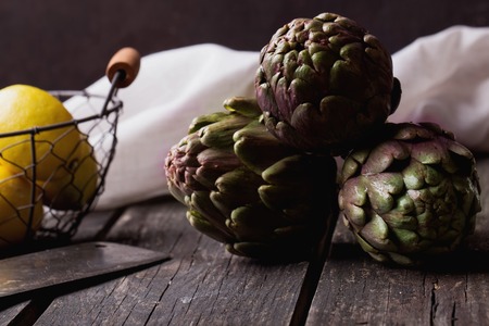Ripe Organic Artichokes on the rustic wooden board  with lemon, napkinの写真素材