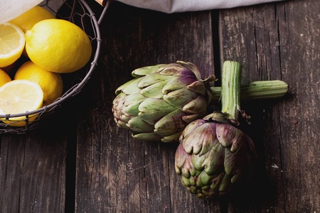 Ripe Organic Artichokes on the rustic wooden board  with lemonの写真素材