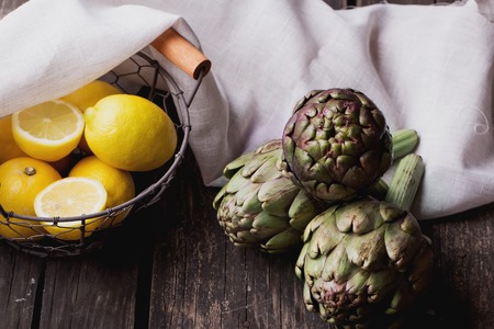 Ripe Organic Artichokes on the rustic wooden board  with lemon, napkinの写真素材