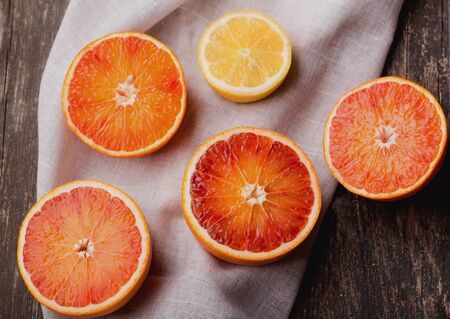 Bio bloody oranges and lemon with napkin on rustic wooden board, cut in halves. Top Viewの写真素材