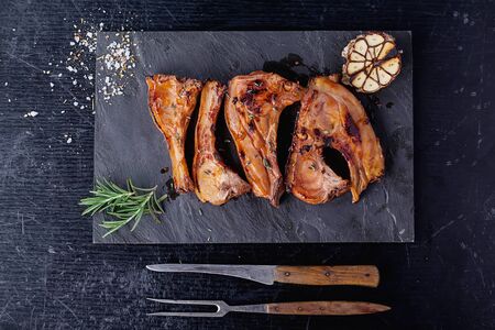 Grilled Pork Ribs in the stone slate board served with grilled garlic and rosemary. Top View
