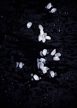 Uncooked Rice on a black slate board. Top Viewの写真素材