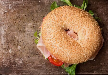 Bagels with Italian ham prosciutto, cream cheese, tomatoes and salad  on rustic metal tray with flowers. Top Viewの写真素材