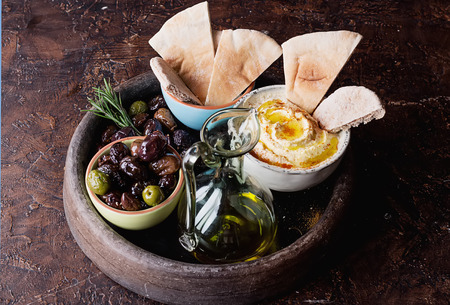 Traditional  Middle east appetizer Hummus served with fresh pita bread, olives, herbs,  seasoned with extra virgin olive oil and paprika  in vintage cermic plate.の写真素材