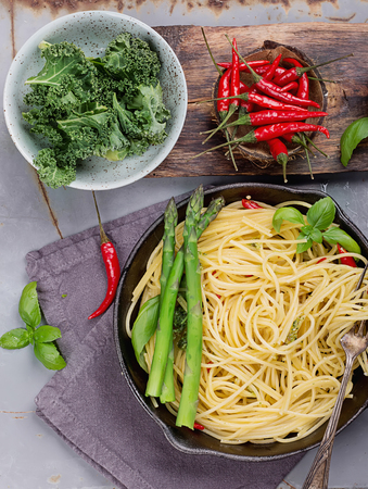 Ready to eat home made Kale Pesto Pasta with Chili oil, asparagus and nuts, served in metal panの写真素材