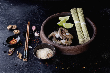 Raw Shrimps ready for cooking on the vintage ceramic plate with dry soba noodles with green tea,...