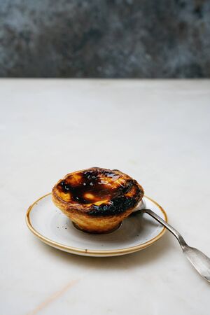  Pastel de nata. Traditional Portuguese dessert, egg tart over marble background in front of rustic metal background. Selective focusの写真素材