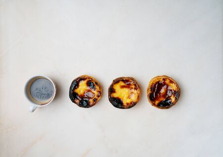 Pastel de nata. Traditional Portuguese dessert, egg tart with cup of coffee over marble background. Top viewの写真素材