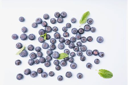 Ripe and juicy fresh blueberries with mint leaves isolated on azure background. Top view