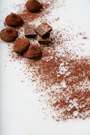 Chocolate candy truffles and chocolate pieces sprinkled with cocoa dust and sea salt over the marble background. Tasty confectionery collection. Selective focusの写真素材