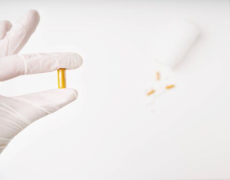 Hand in medicine disposable glove with capsule pill on the forefront. Medical pills and capsules...