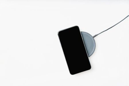 Smartphone on a wireless charger isolated over white background. Top view. Copy space.の写真素材