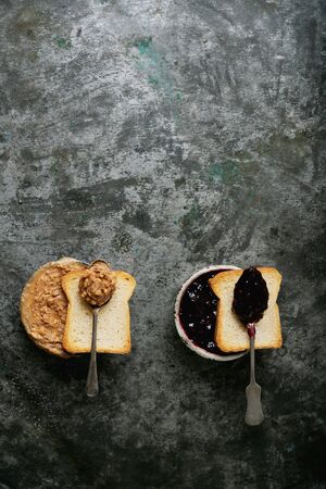 Peanut butter and raspberry jelly bowls with crispy toasts over rustic metal background. Top view. Breakfast sandwiches preparation.の写真素材