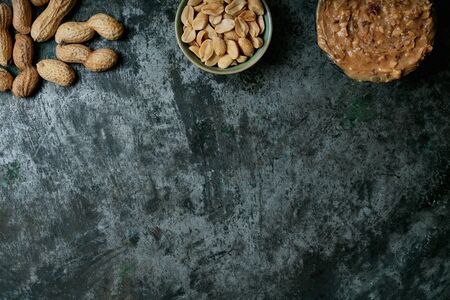 Heap of peanuts in a shell, bowl of roasted salted peanuts and bowl of peanut butter over metal rustic background. Peanut production concept. Copy space. Top view.の写真素材