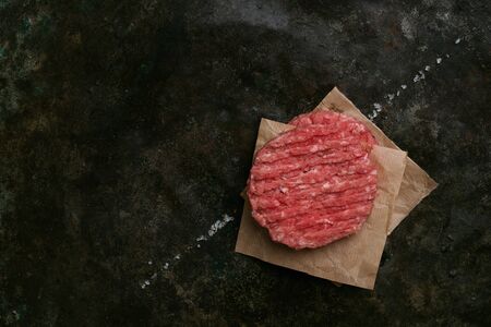 Raw Ground beef meat Burger steak cutlets with seasoning on rustic metal background. Top view