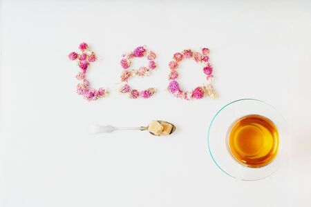 Cup of herbal tea over white marble background. Food typography. Word "tea" made of dry globe amaranth flowers. Top view. Copy space.の写真素材