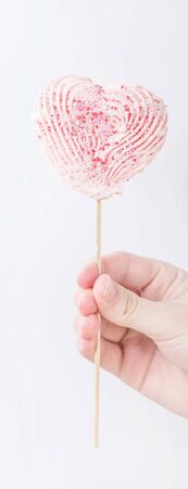 Child hand holding straw with heart shaped meringue