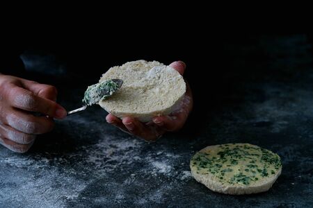Traditional Portuguese flat circular bread Bolo Do Caco. Female hands buttering the bread. Madeira island cuisine. Selective focusの写真素材
