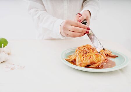 Raw chicken wings in Korean marinade with gochuang paste, honey, garlic, soy sauce and spices. Chef grating garlic over wings. Cooking process. の写真素材